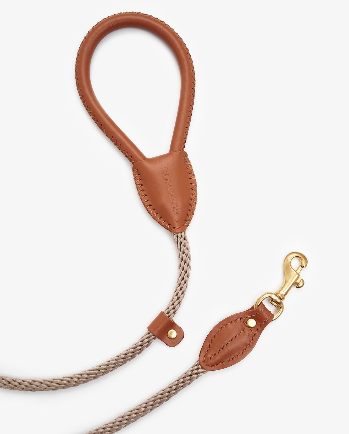 Coiled view of a premium rope dog leash with brown leather accents and elegant brass hook