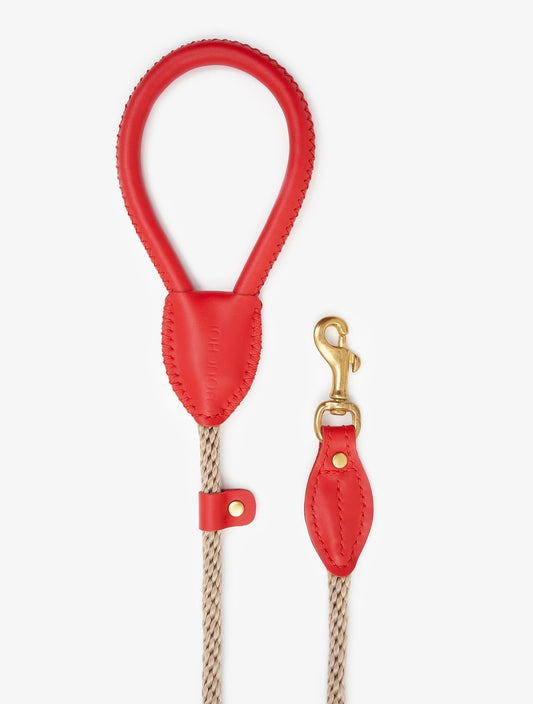 Coiled view of a premium rope dog leash with red leather accents and elegant brass hook