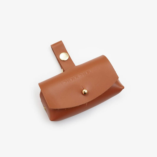 Brown Italian leather dog waste bag dispenser with gold hardware on a white background