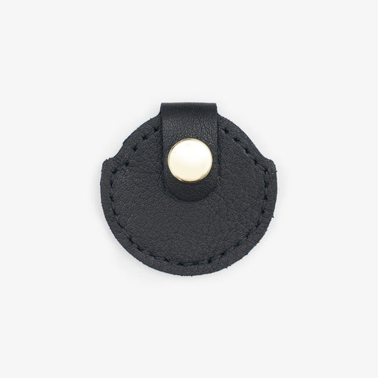 Black leather AirTag holder with gold button, handmade from Italian leather on a white background