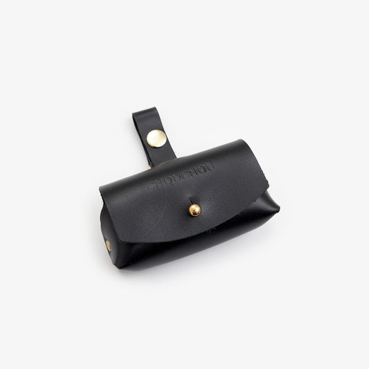 Black Italian leather dog waste bag dispenser with gold hardware on a white background